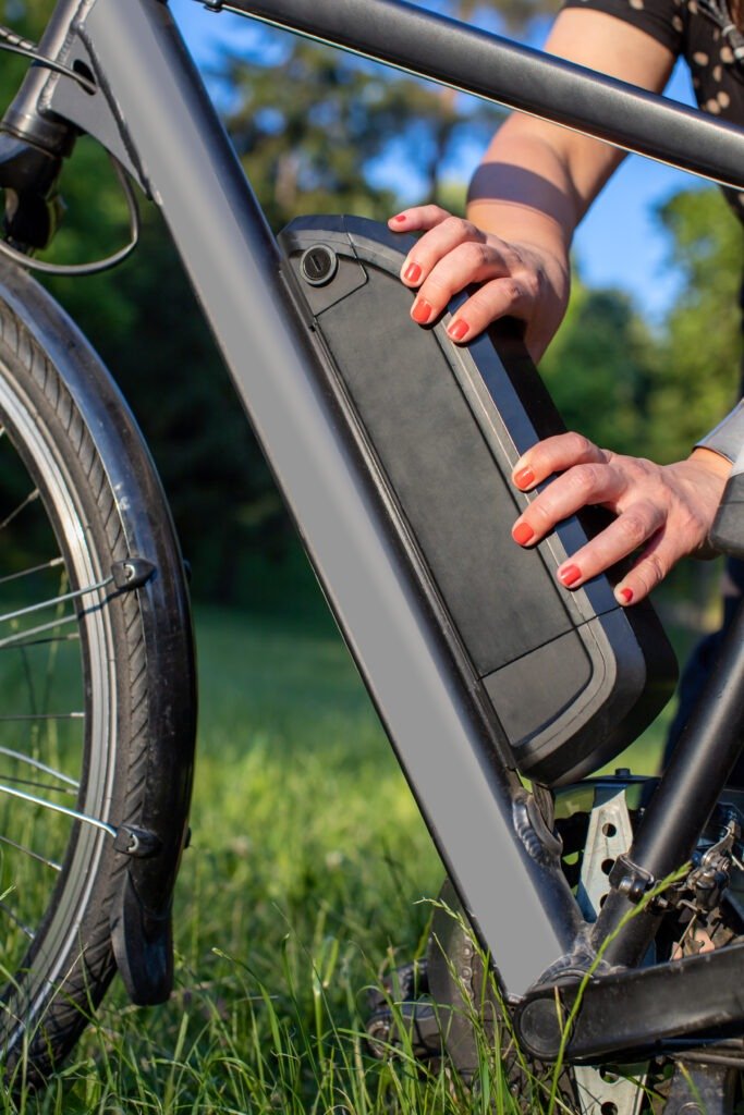 E-bike battery Woman holding an electric bike battery mounted on frame