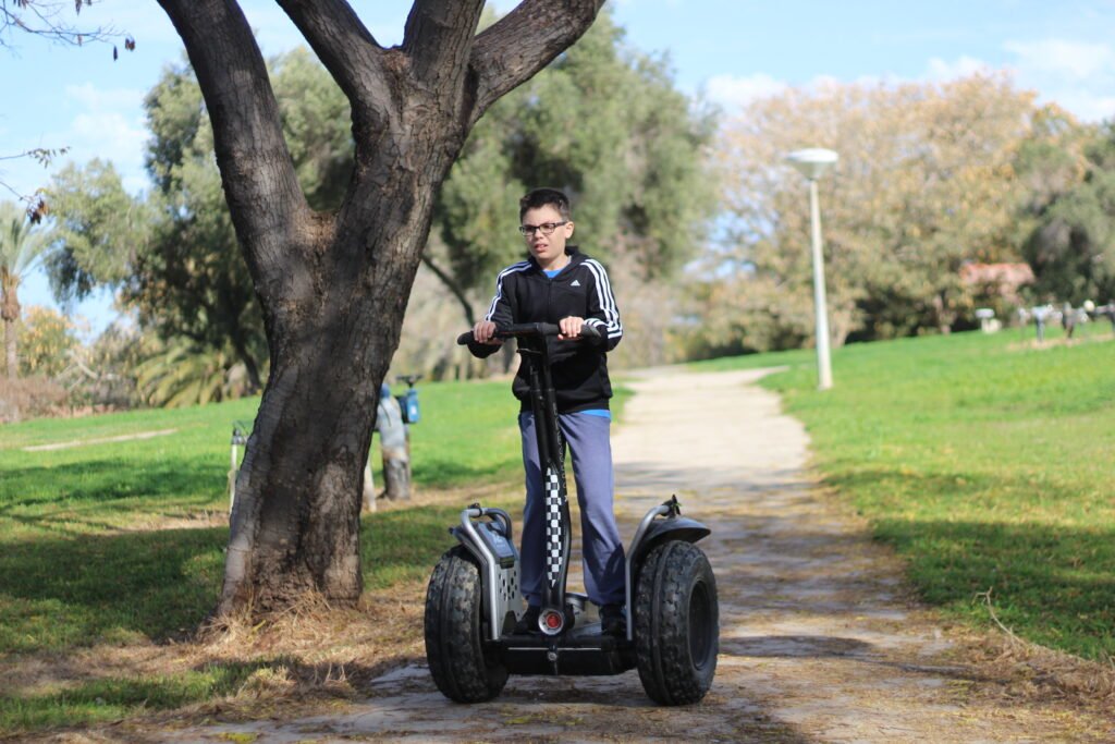 Boy riding his hoverboard with huge wheels in the park
