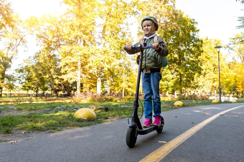 Child riding an electric scooter wearing a safety helmet