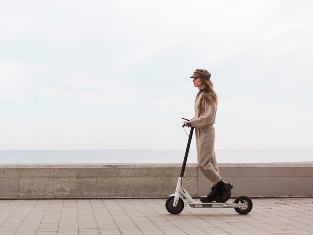 Young woman riding an electric scooter on see side Young woman riding an electric scooter on see side
